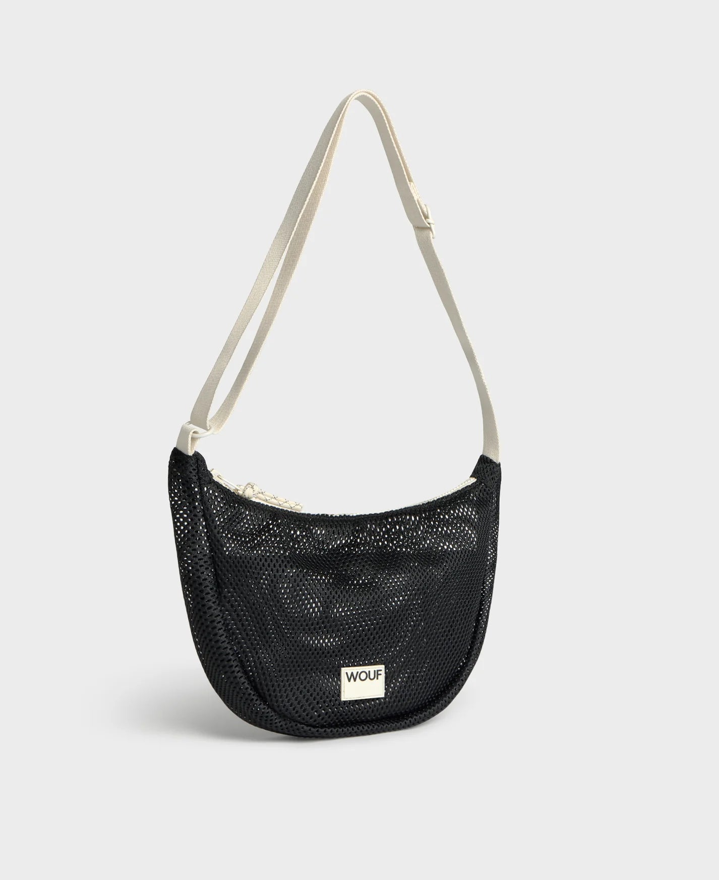 Bolso bandolera de color negro puro, de diseño estructurado con correa cruzada ajustable de algodón, cremallera superior y etiqueta de silicona, modelo Onyx de Wouf.