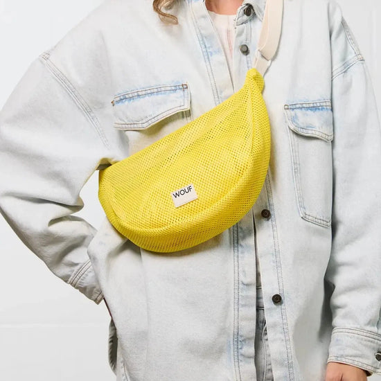 Bolso bandolera de color amarillo en tejido de rejilla (mesh) con correa cruzada ajustable de algodón, cremallera superior y etiqueta frontal de silicona, modelo Ray de Wouf.