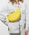 Bolso bandolera de color amarillo en tejido de rejilla (mesh) con correa cruzada ajustable de algodón, cremallera superior y etiqueta frontal de silicona, modelo Ray de Wouf.