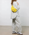 Bolso bandolera de color amarillo en tejido de rejilla (mesh) con correa cruzada ajustable de algodón, cremallera superior y etiqueta frontal de silicona, modelo Ray de Wouf.