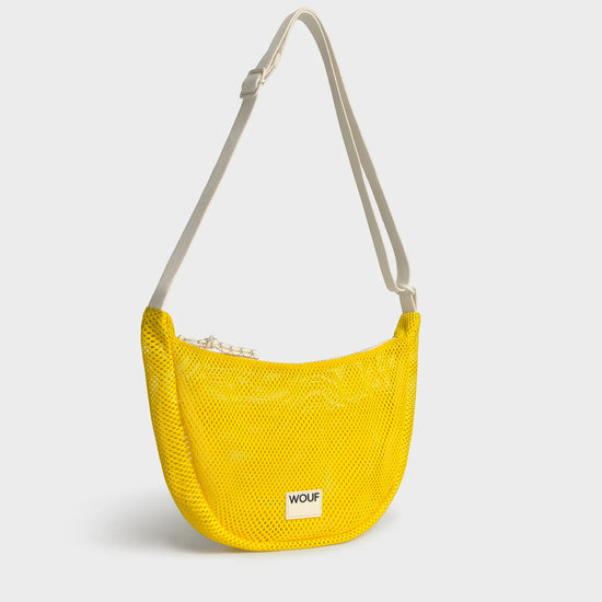 Bolso bandolera de color amarillo en tejido de rejilla (mesh) con correa cruzada ajustable de algodón, cremallera superior y etiqueta frontal de silicona, modelo Ray de Wouf.