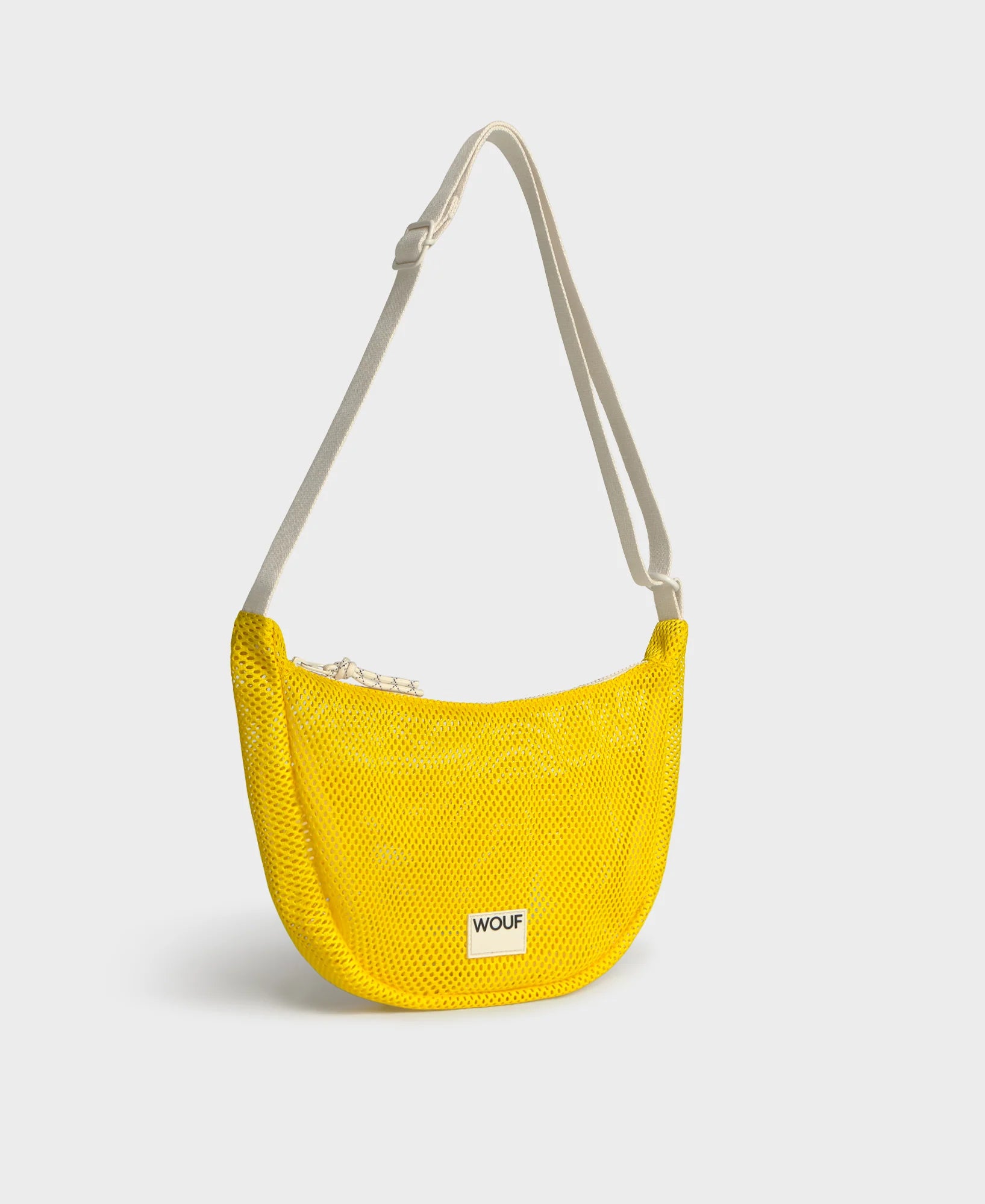 Bolso bandolera de color amarillo en tejido de rejilla (mesh) con correa cruzada ajustable de algodón, cremallera superior y etiqueta frontal de silicona, modelo Ray de Wouf.