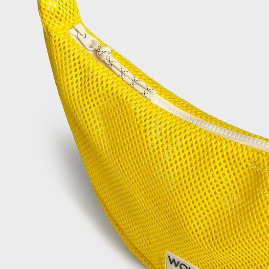 Bolso bandolera de color amarillo en tejido de rejilla (mesh) con correa cruzada ajustable de algodón, cremallera superior y etiqueta frontal de silicona, modelo Ray de Wouf.