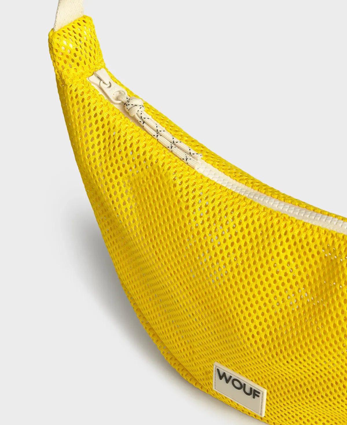 Bolso bandolera de color amarillo en tejido de rejilla (mesh) con correa cruzada ajustable de algodón, cremallera superior y etiqueta frontal de silicona, modelo Ray de Wouf.