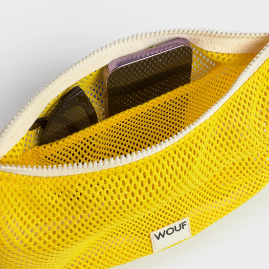 Bolso bandolera de color amarillo en tejido de rejilla (mesh) con correa cruzada ajustable de algodón, cremallera superior y etiqueta frontal de silicona, modelo Ray de Wouf.