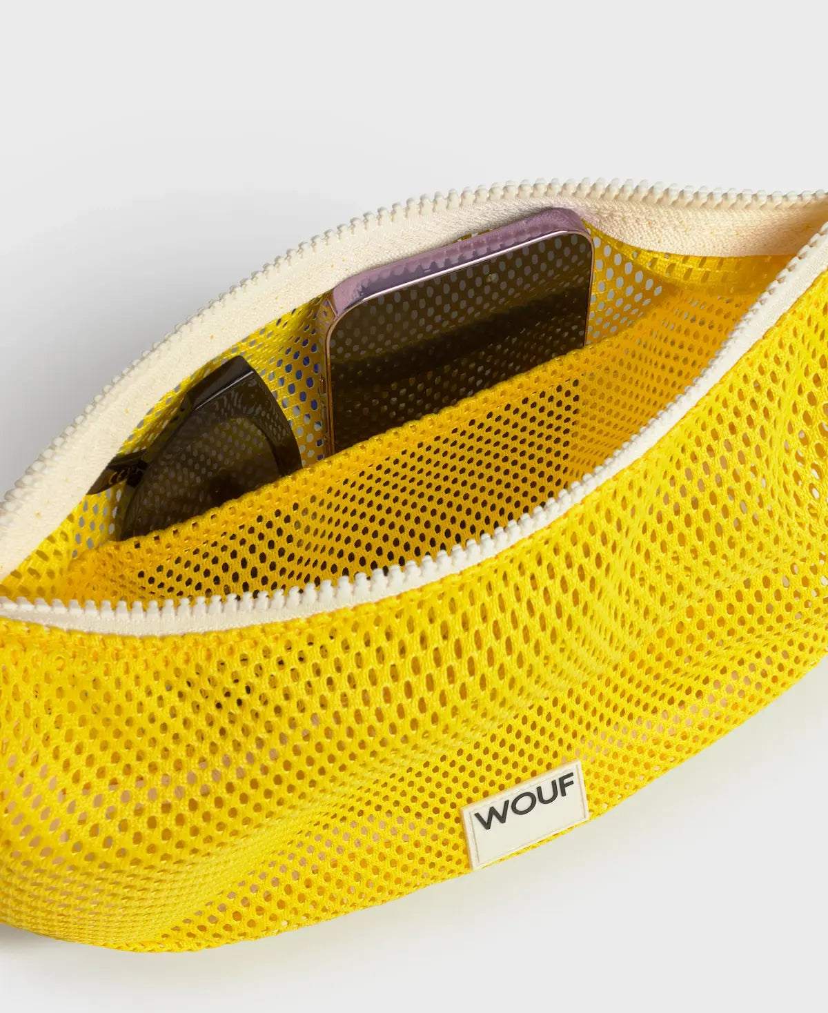 Bolso bandolera de color amarillo en tejido de rejilla (mesh) con correa cruzada ajustable de algodón, cremallera superior y etiqueta frontal de silicona, modelo Ray de Wouf.