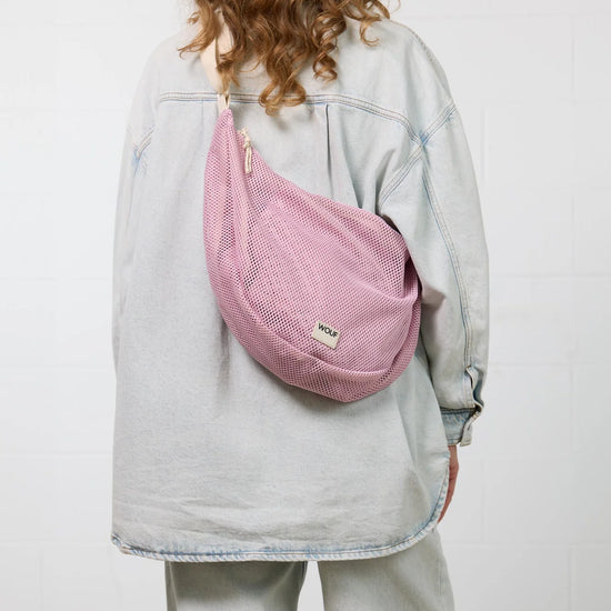 Bolso cruzado de gran tamaño color rosa empolvado en tejido de rejilla (mesh) con correa ajustable de algodón, cremallera superior y bolsillos interiores, marca Wouf.