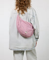 Bolso cruzado de gran tamaño color rosa empolvado en tejido de rejilla (mesh) con correa ajustable de algodón, cremallera superior y bolsillos interiores, marca Wouf.