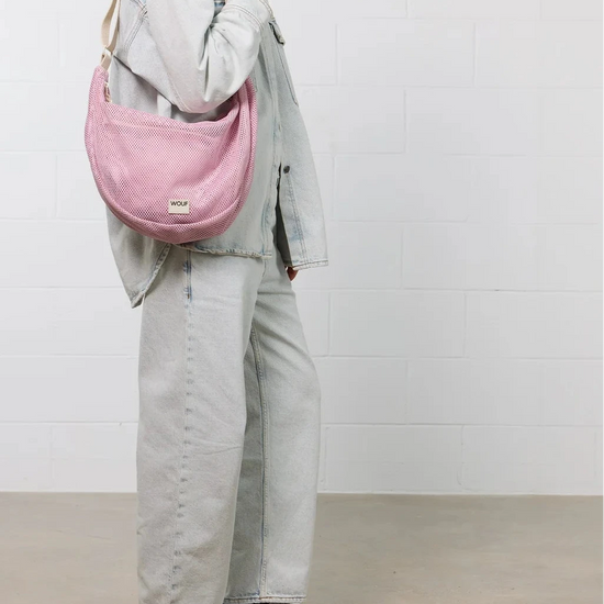 Bolso cruzado de gran tamaño color rosa empolvado en tejido de rejilla (mesh) con correa ajustable de algodón, cremallera superior y bolsillos interiores, marca Wouf.