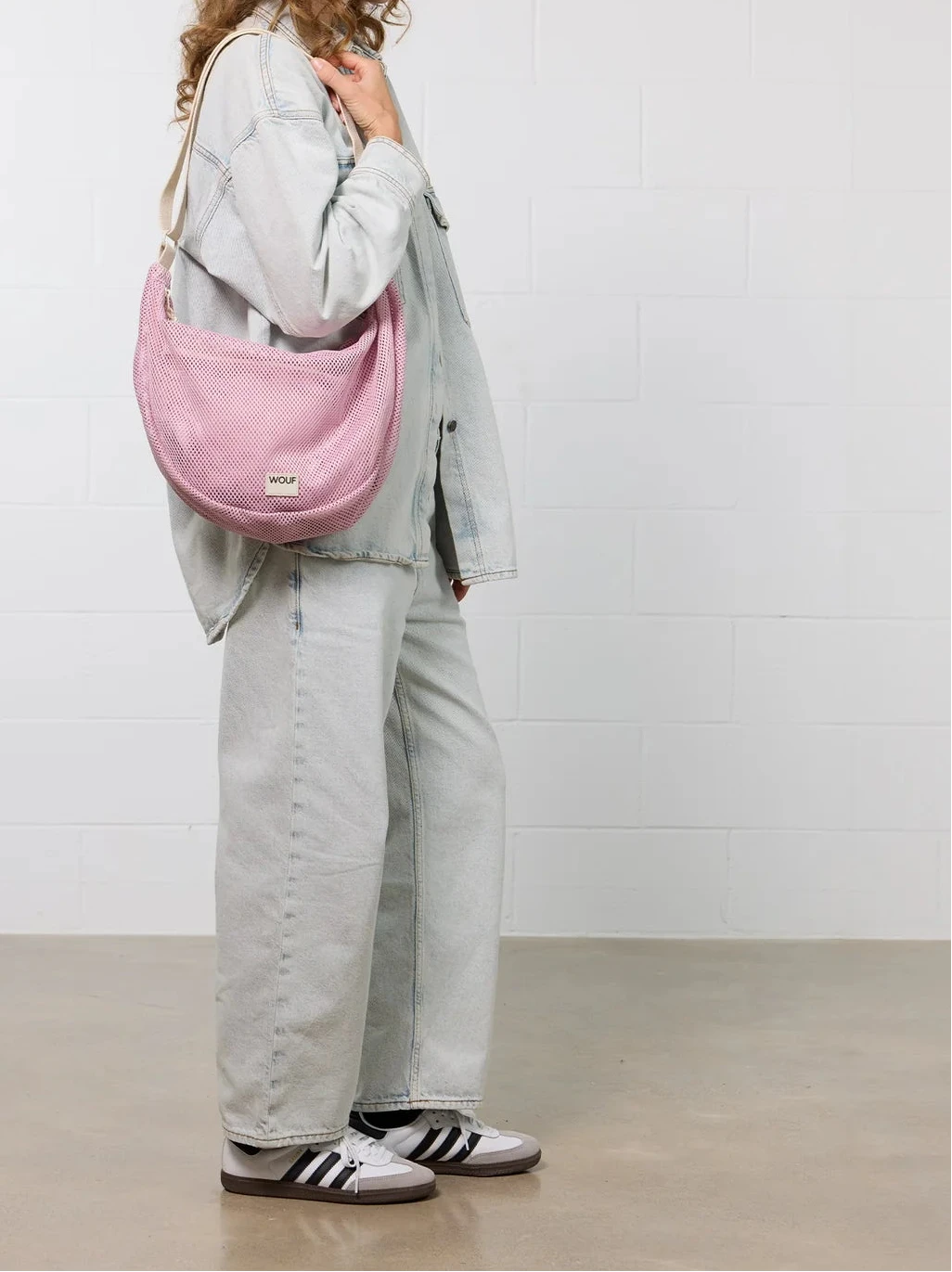 Bolso cruzado de gran tamaño color rosa empolvado en tejido de rejilla (mesh) con correa ajustable de algodón, cremallera superior y bolsillos interiores, marca Wouf.