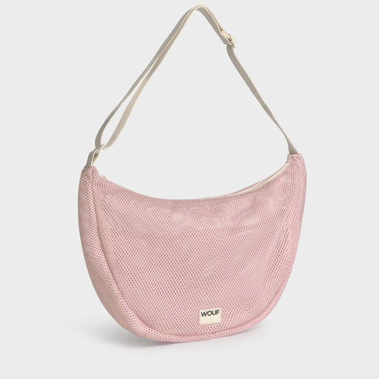 Bolso cruzado de gran tamaño color rosa empolvado en tejido de rejilla (mesh) con correa ajustable de algodón, cremallera superior y bolsillos interiores, marca Wouf.