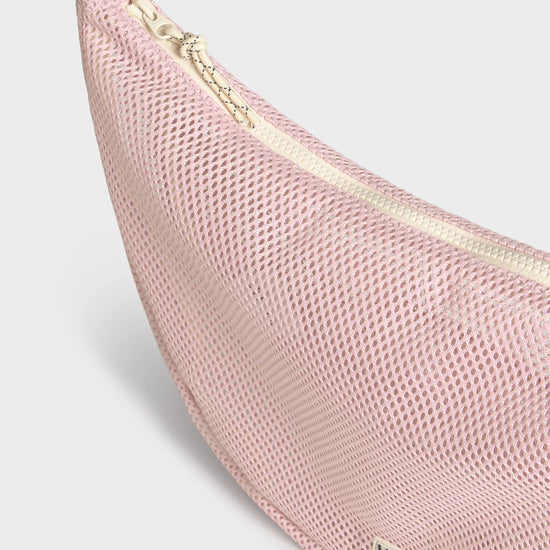 Bolso cruzado de gran tamaño color rosa empolvado en tejido de rejilla (mesh) con correa ajustable de algodón, cremallera superior y bolsillos interiores, marca Wouf.