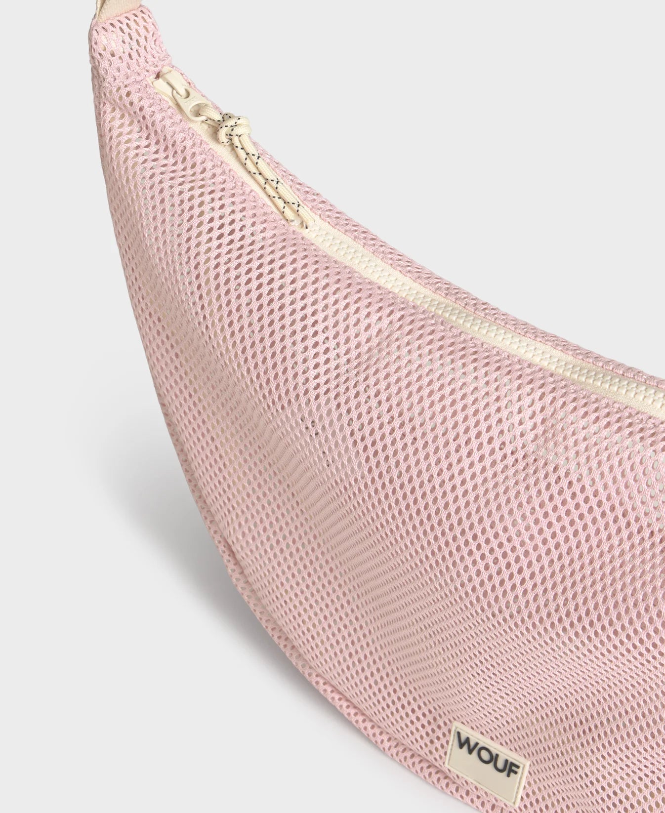 Bolso cruzado de gran tamaño color rosa empolvado en tejido de rejilla (mesh) con correa ajustable de algodón, cremallera superior y bolsillos interiores, marca Wouf.