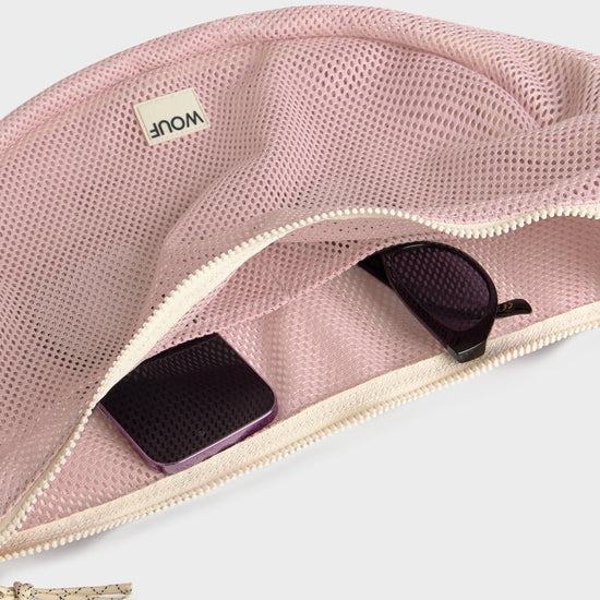 Bolso cruzado de gran tamaño color rosa empolvado en tejido de rejilla (mesh) con correa ajustable de algodón, cremallera superior y bolsillos interiores, marca Wouf.
