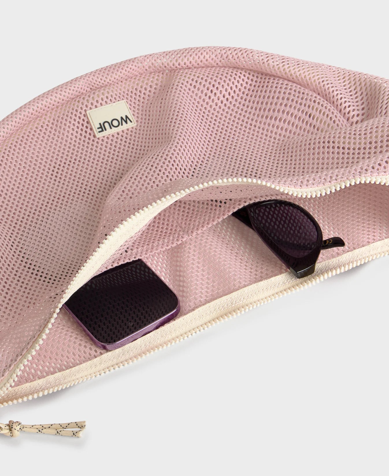 Bolso cruzado de gran tamaño color rosa empolvado en tejido de rejilla (mesh) con correa ajustable de algodón, cremallera superior y bolsillos interiores, marca Wouf.