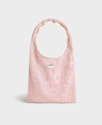 Bolso grande tipo camiseta de color rosa empolvado en tejido de rejilla (mesh) con asas integradas y etiqueta frontal de silicona, marca Wouf.