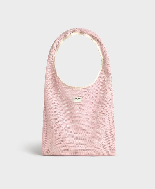Bolso grande tipo camiseta de color rosa empolvado en tejido de rejilla (mesh) con asas integradas y etiqueta frontal de silicona, marca Wouf.