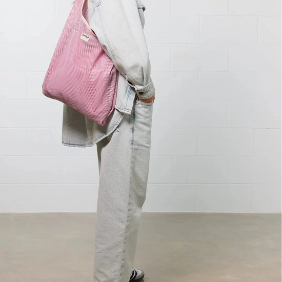 Bolso grande tipo camiseta de color rosa empolvado en tejido de rejilla (mesh) con asas integradas y etiqueta frontal de silicona, marca Wouf.