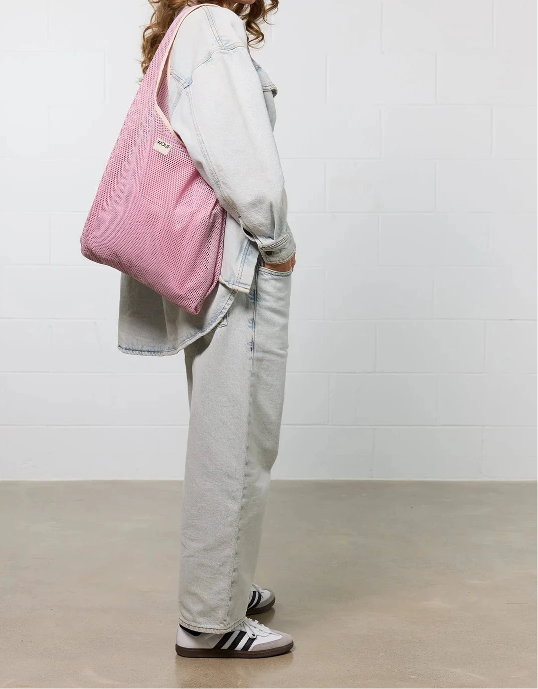 Bolso grande tipo camiseta de color rosa empolvado en tejido de rejilla (mesh) con asas integradas y etiqueta frontal de silicona, marca Wouf.