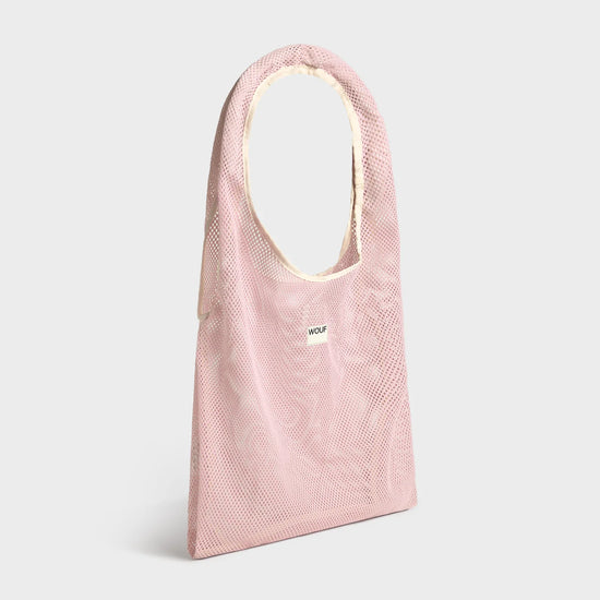 Bolso grande tipo camiseta de color rosa empolvado en tejido de rejilla (mesh) con asas integradas y etiqueta frontal de silicona, marca Wouf.