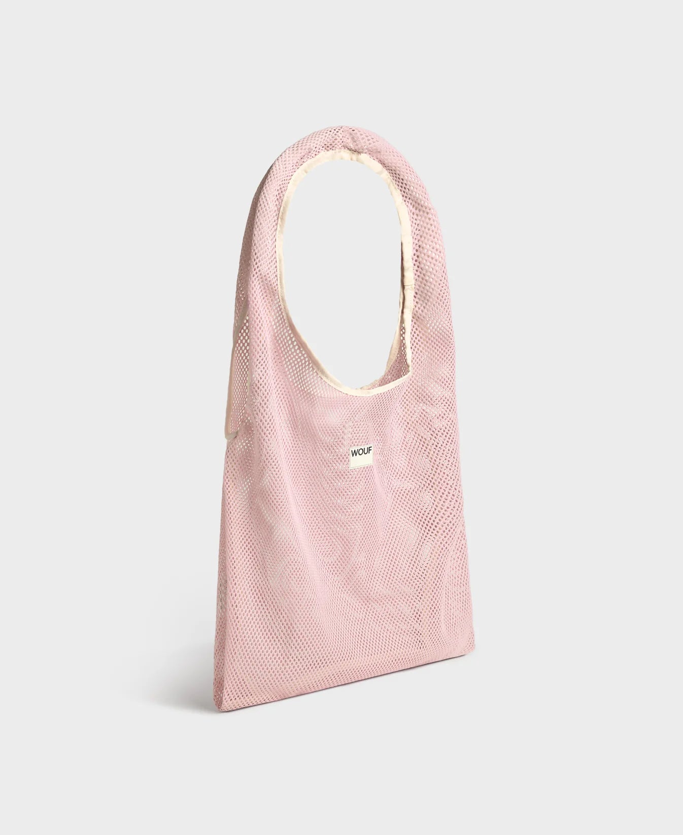 Bolso grande tipo camiseta de color rosa empolvado en tejido de rejilla (mesh) con asas integradas y etiqueta frontal de silicona, marca Wouf.