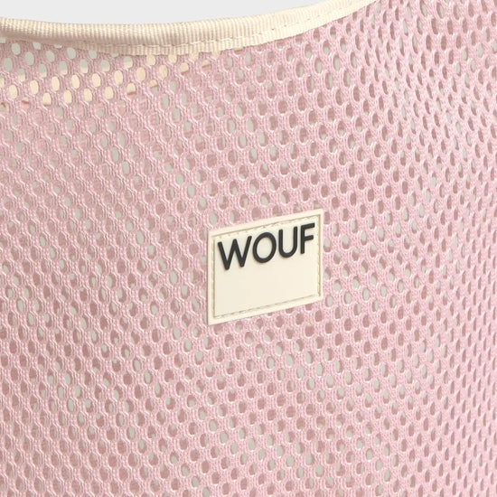 Bolso grande tipo camiseta de color rosa empolvado en tejido de rejilla (mesh) con asas integradas y etiqueta frontal de silicona, marca Wouf.