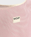 Bolso grande tipo camiseta de color rosa empolvado en tejido de rejilla (mesh) con asas integradas y etiqueta frontal de silicona, marca Wouf.