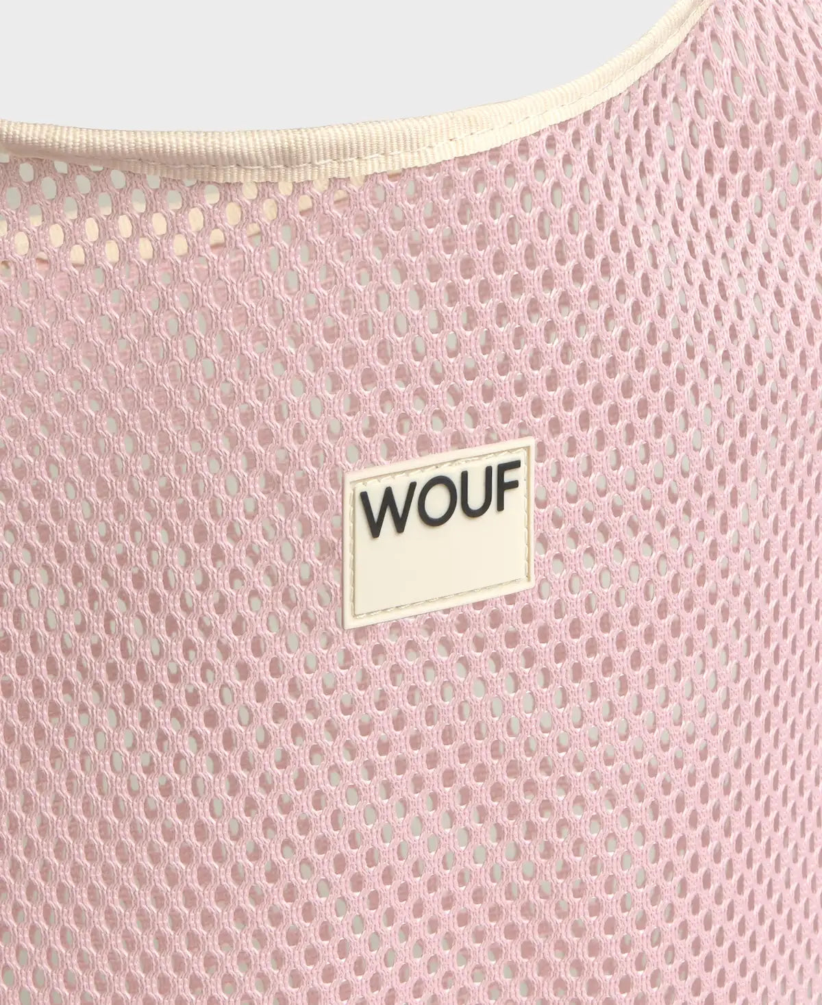 Bolso grande tipo camiseta de color rosa empolvado en tejido de rejilla (mesh) con asas integradas y etiqueta frontal de silicona, marca Wouf.