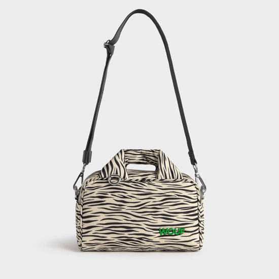 Bolso tipo bowling con estampado animal print de cebra, logo metálico frontal, asas cortas acolchadas y correa larga extraíble, modelo Zebra Hit de Wouf.