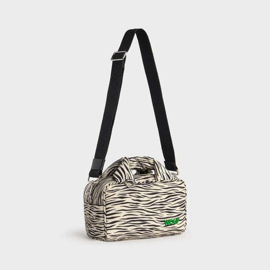 Bolso tipo bowling con estampado animal print de cebra, logo metálico frontal, asas cortas acolchadas y correa larga extraíble, modelo Zebra Hit de Wouf.