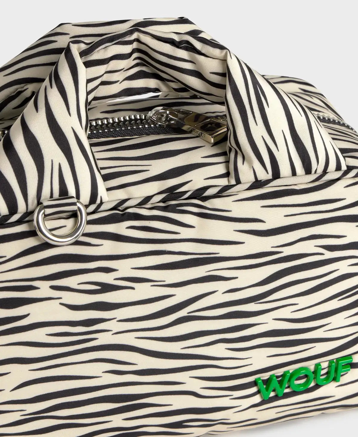 Bolso tipo bowling con estampado animal print de cebra, logo metálico frontal, asas cortas acolchadas y correa larga extraíble, modelo Zebra Hit de Wouf.