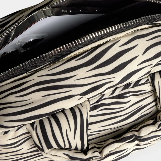 Bolso tipo bowling con estampado animal print de cebra, logo metálico frontal, asas cortas acolchadas y correa larga extraíble, modelo Zebra Hit de Wouf.