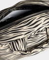 Bolso tipo bowling con estampado animal print de cebra, logo metálico frontal, asas cortas acolchadas y correa larga extraíble, modelo Zebra Hit de Wouf.