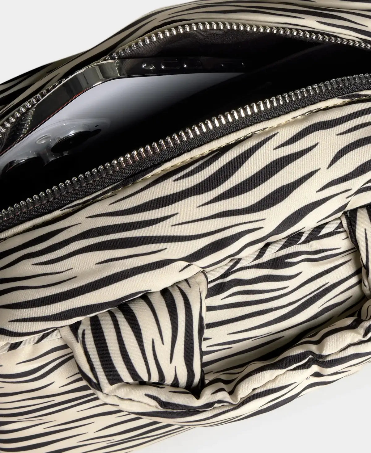 Bolso tipo bowling con estampado animal print de cebra, logo metálico frontal, asas cortas acolchadas y correa larga extraíble, modelo Zebra Hit de Wouf.