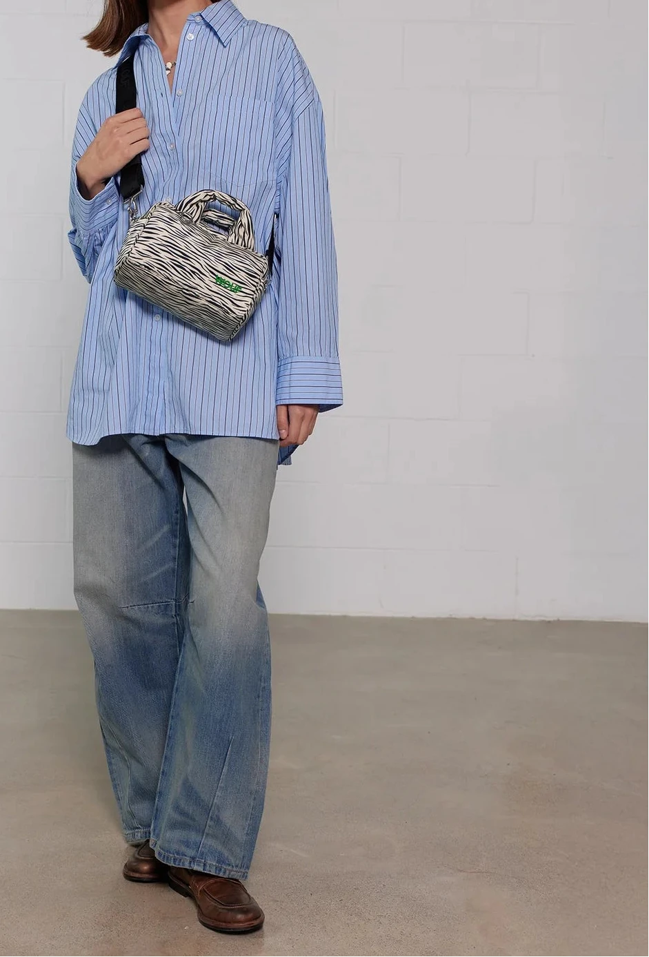 Bolso tipo bowling con estampado animal print de cebra, logo metálico frontal, asas cortas acolchadas y correa larga extraíble, modelo Zebra Hit de Wouf.