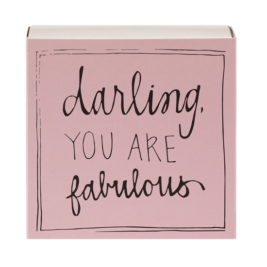 Caja de cerillas cuadrada de color rosa con el texto 'Darling you are fabulous' impreso, que contiene 125 cerillas largas de madera negra y punta blanca.