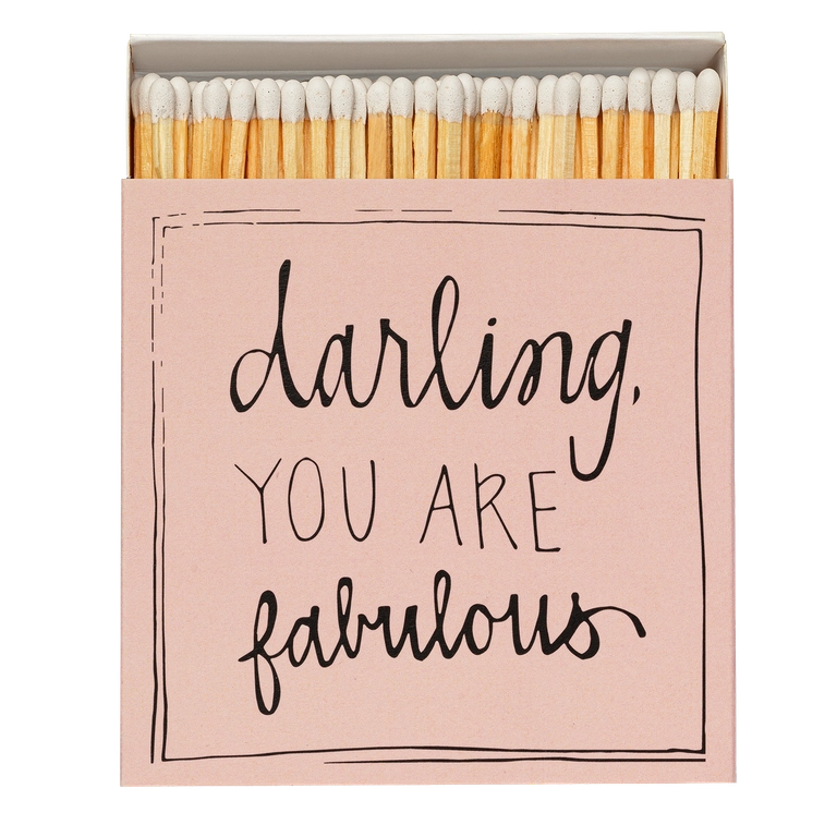 Caja de cerillas cuadrada de color rosa con el texto 'Darling you are fabulous' impreso, que contiene 125 cerillas largas de madera negra y punta blanca.