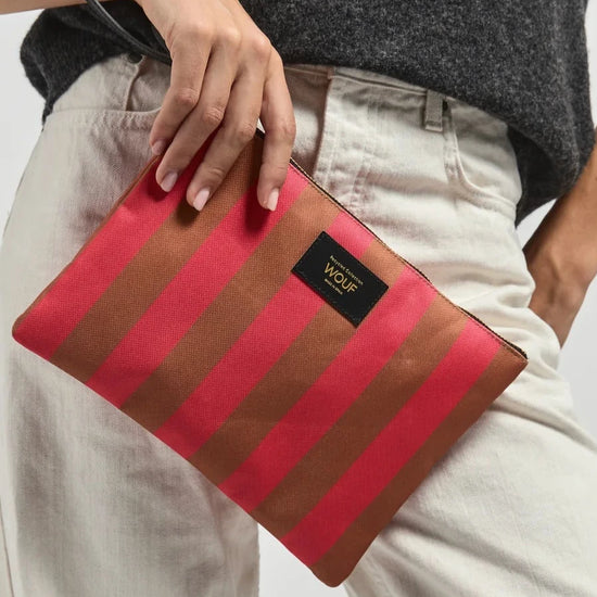 Bolso de mano tipo sobre de gran tamaño con estampado de rayas en tonos naranja y rosa, con cierre de cremallera superior y etiqueta de cuero