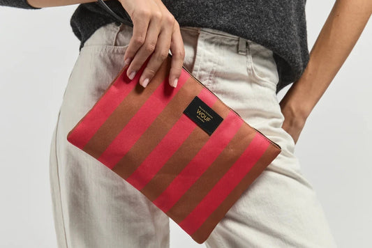 Bolso de mano tipo sobre de gran tamaño con estampado de rayas en tonos naranja y rosa, con cierre de cremallera superior y etiqueta de cuero