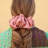 Coletero tipo scrunchie de satén plisado en color rosa antiguo con acabado brillante y diseño ondulado de la marca danesa By Stær.