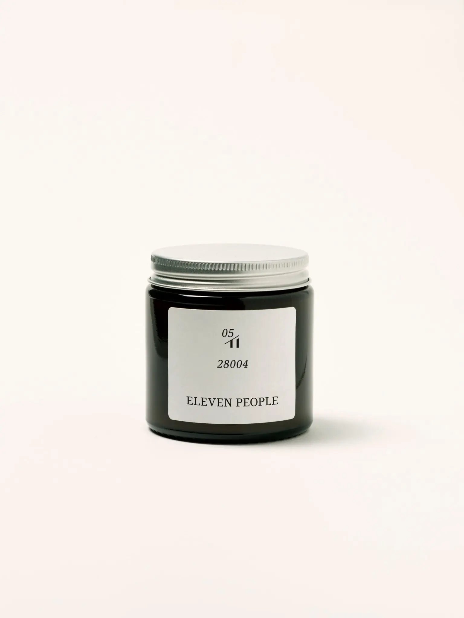 Vela aromática en envase de vidrio ámbar, colección 05 28004 de Eleven People, fragancia grosella negra abedul y musgo de roble, elaborada artesanalmente en Asturias